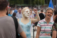 Maskenfigur geht mit Bademantel spazieren, Zuschauer lachen