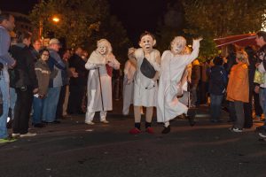 Vier Maskenfiguren winken bei der Stamp Parade in Hamburg